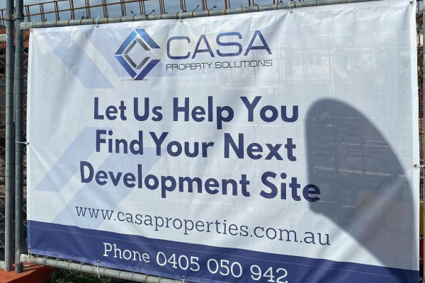 PVC Banner with blue and white text, installed on a wire temporary fence