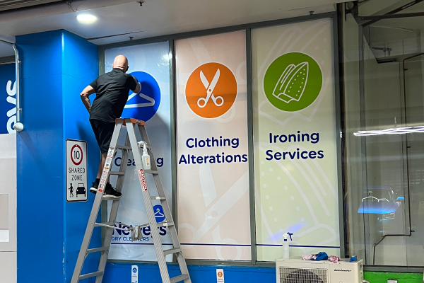 External window graphics being installed by man on ladder