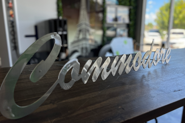 Stainless steel house sign with pin mounts displayed on a desk