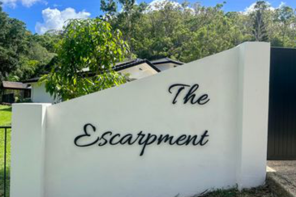 Black steel house sign installed on external rendered fence
