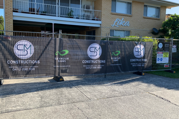 a construction fence banner installed to the temporary fencing outside an apartment block