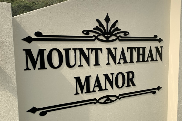 Black ACM cutout signage installed onto an external rendered fence