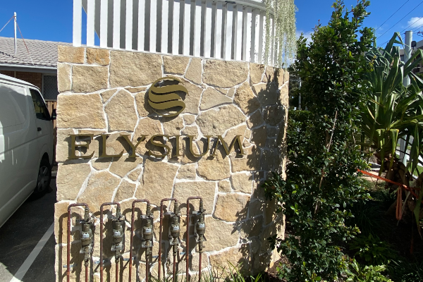 Gold 3D cutout letters installed onto face of building fence wall