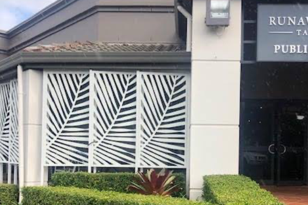 White palm leaf inspired decorative screens installed in a row of 3 to front of building